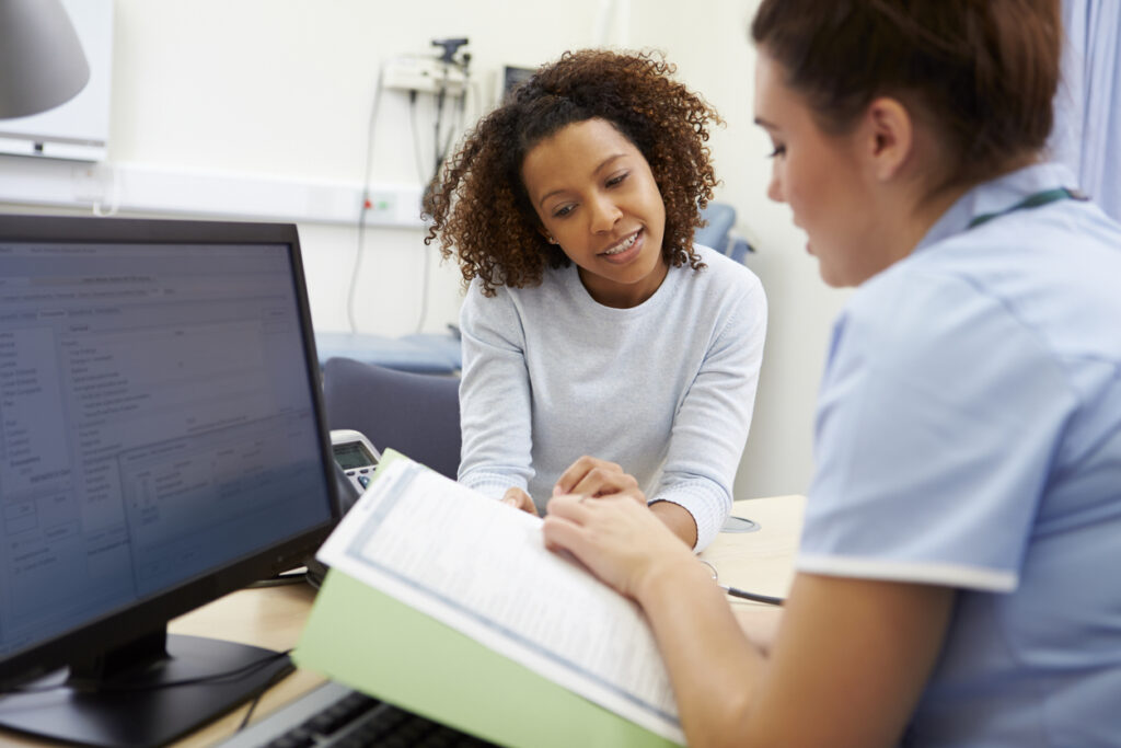 Nurse Discussing Test Results With Patient In Office Looking At Documents